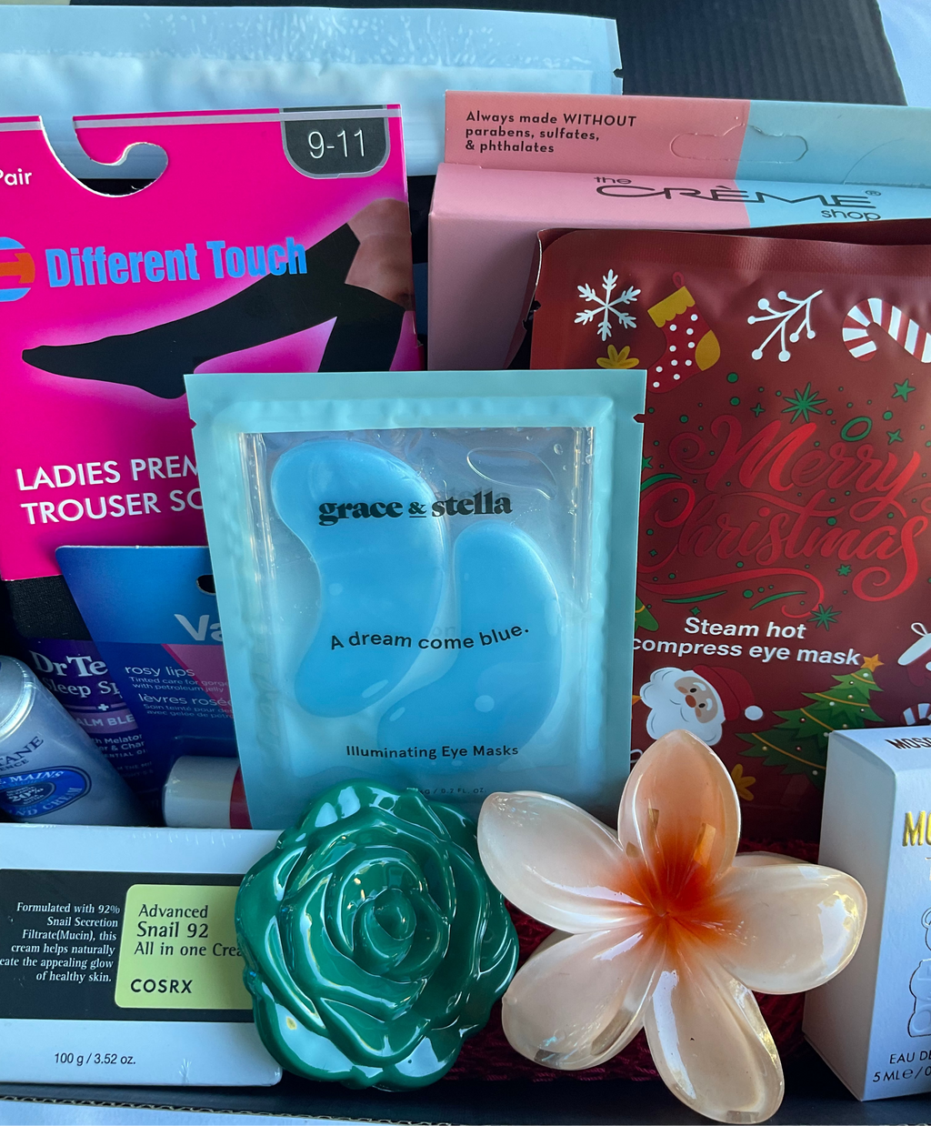 Assorted beauty products including eye masks and a flower on a table.